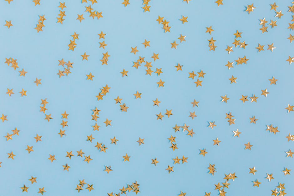 Gold star confetti scattered over a light blue surface