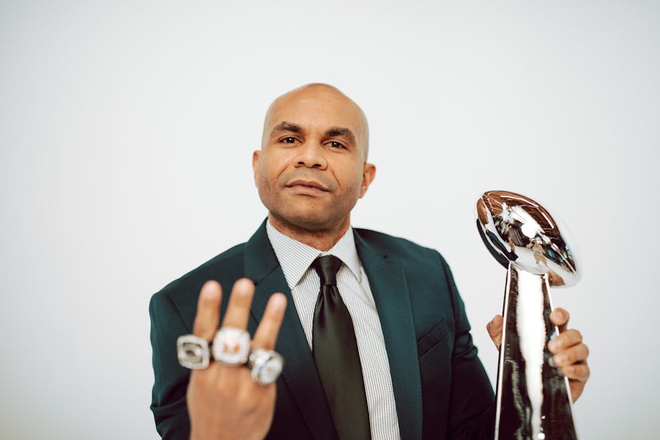 Confident man in a suit showcasing victory rings and trophy