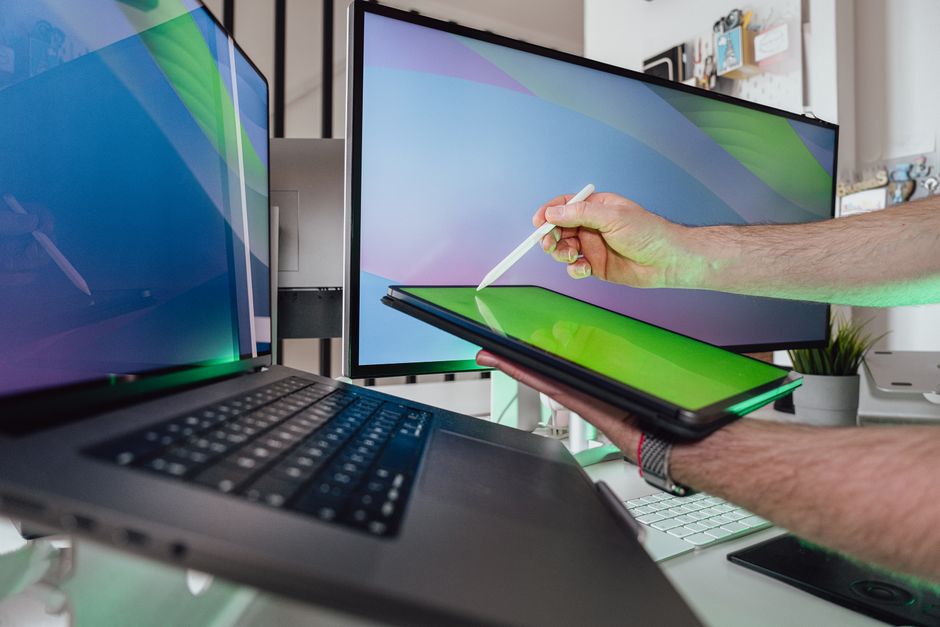 Person using stylus on tablet with dual monitors