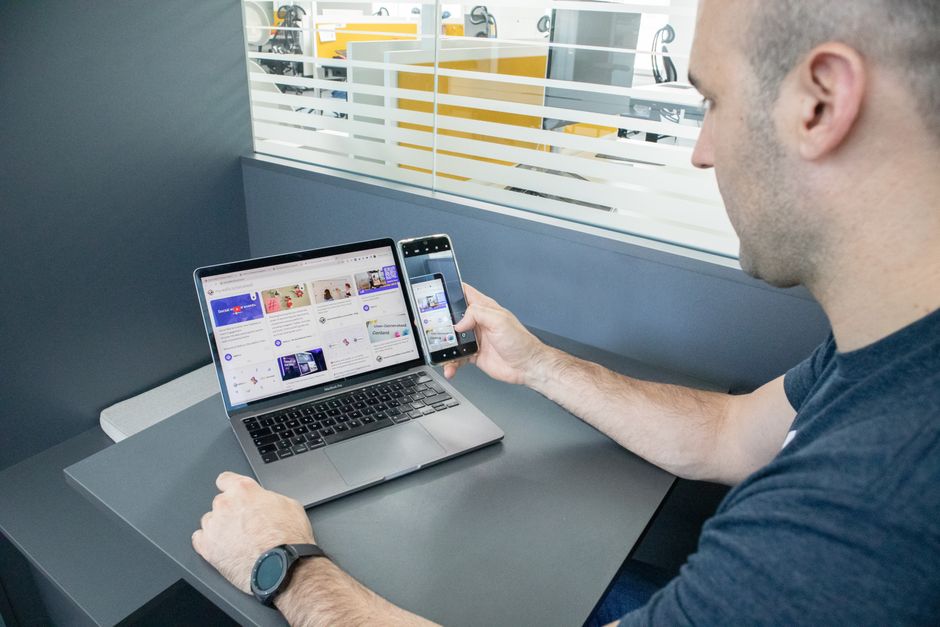 A man multitasking with a laptop and smartphone in a contemporary office space.