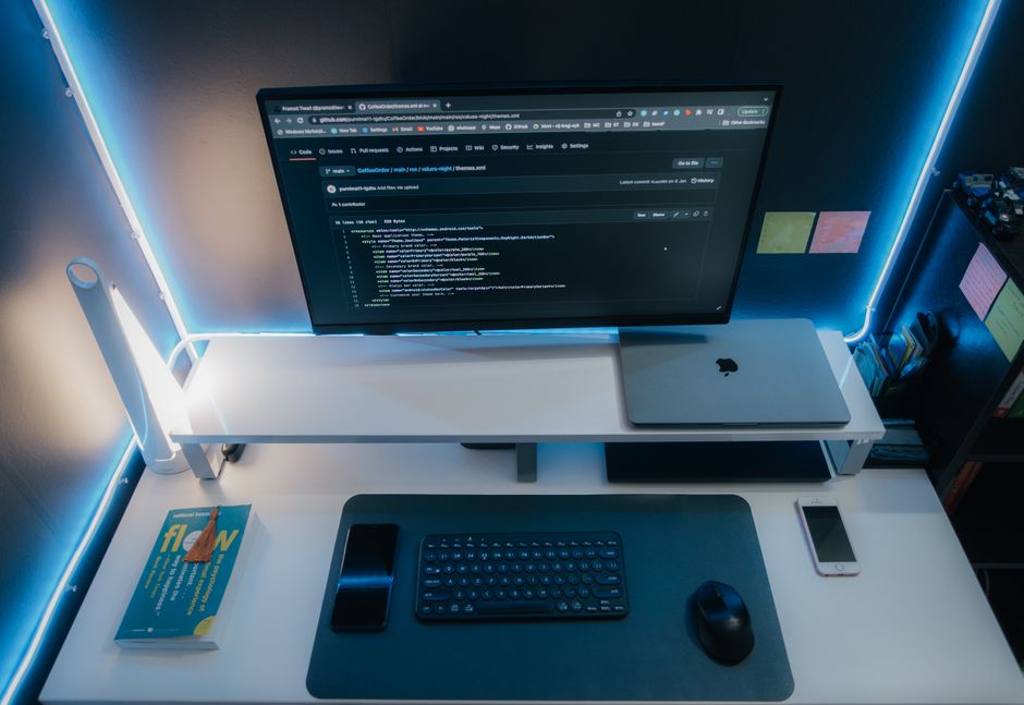 A minimalist workspace with a computer setup, gadgets, and neon lighting for a sleek modern look